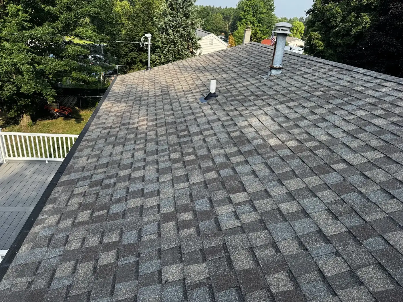 An asphalt roof with a chimney and vent pipe, two of the most common places a roof leaks.
