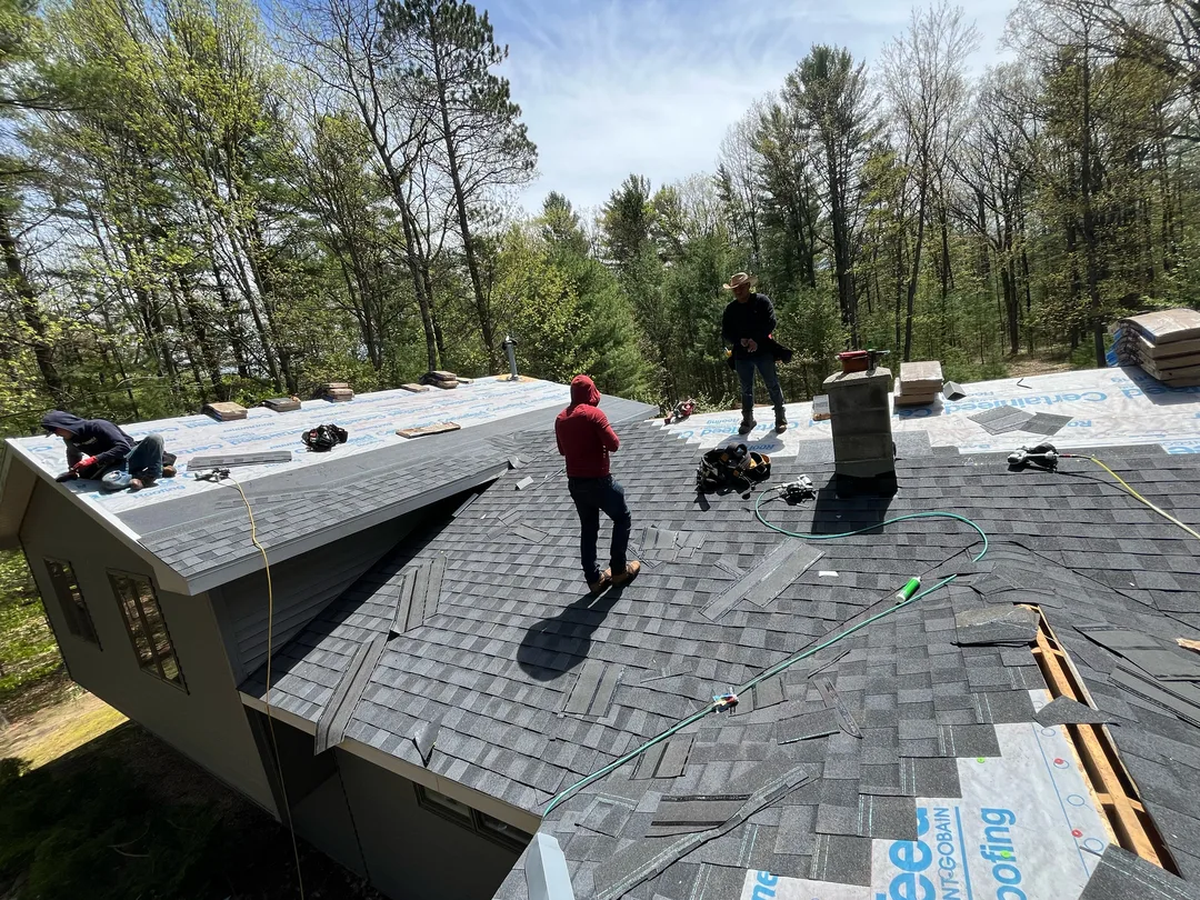 A Falcon Roofing crew installing a new asphalt shingle roof on a Traverse City home.