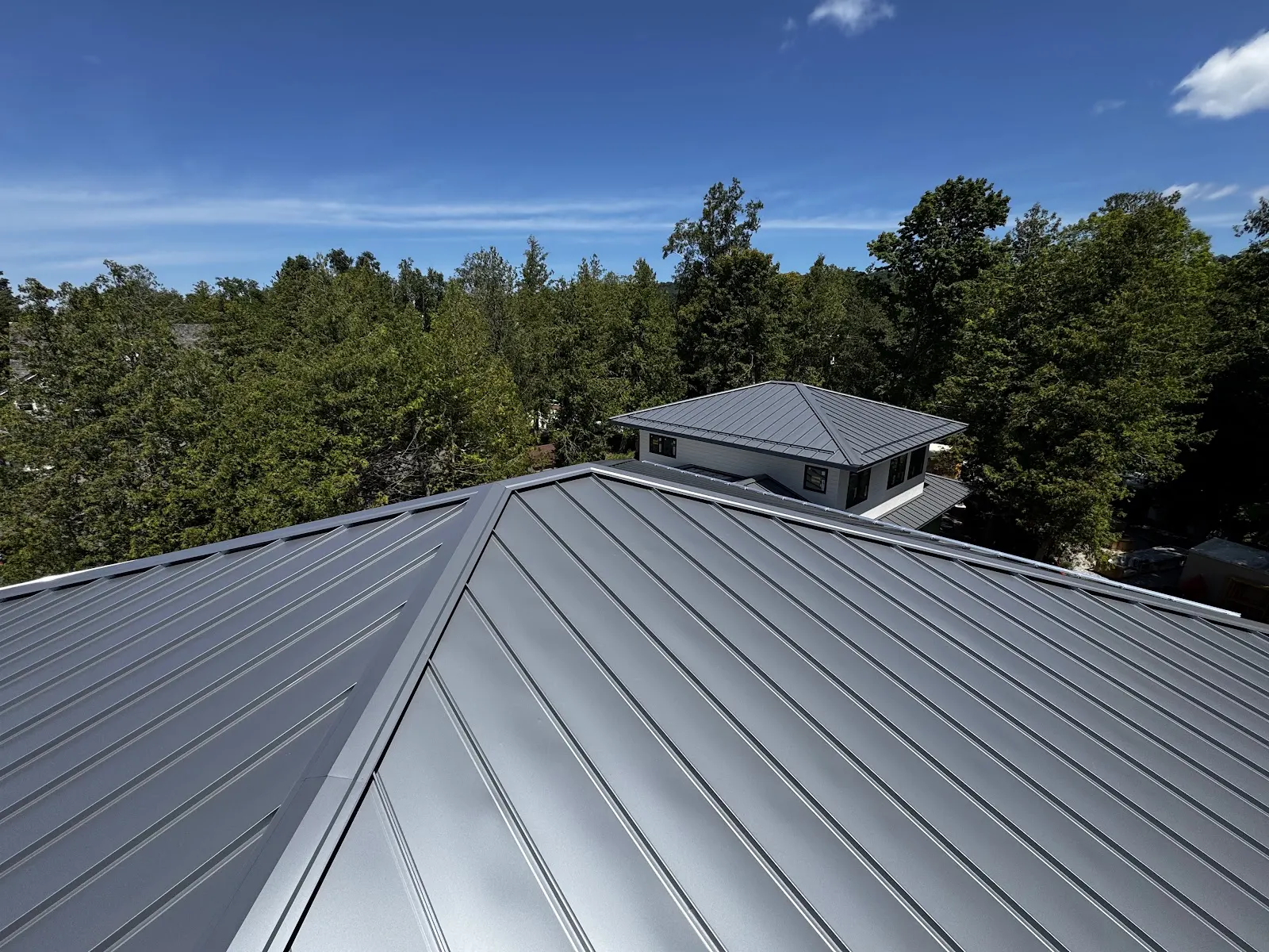 A durable metal roof on a Northern Michigan home under a clear blue sky.