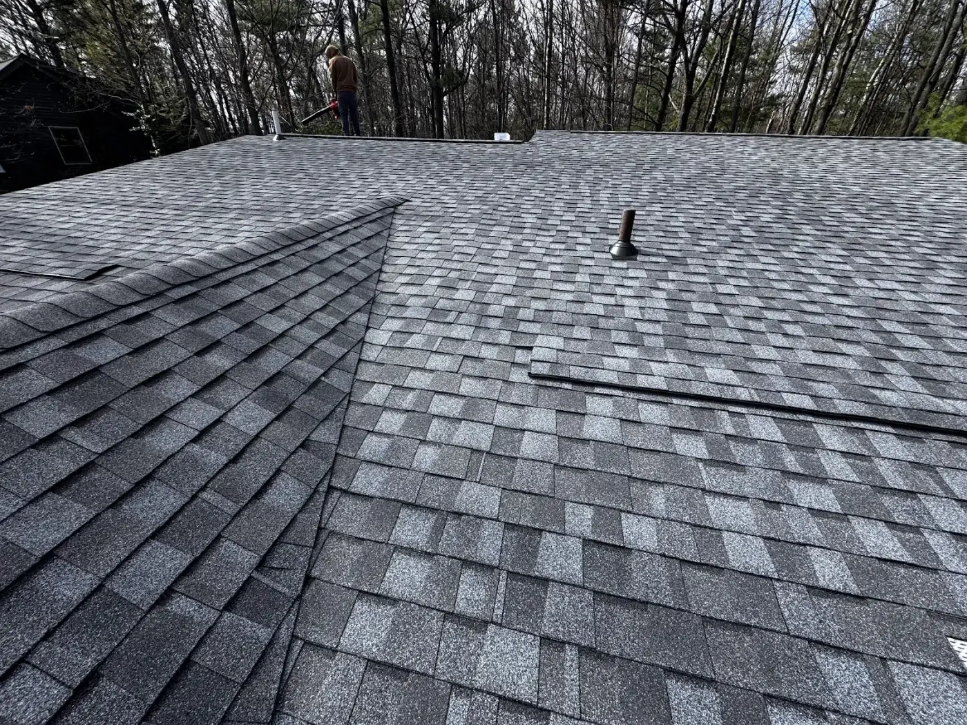A Falcon Roofing technician clearing debris while inspecting a Northern Michigan roof.