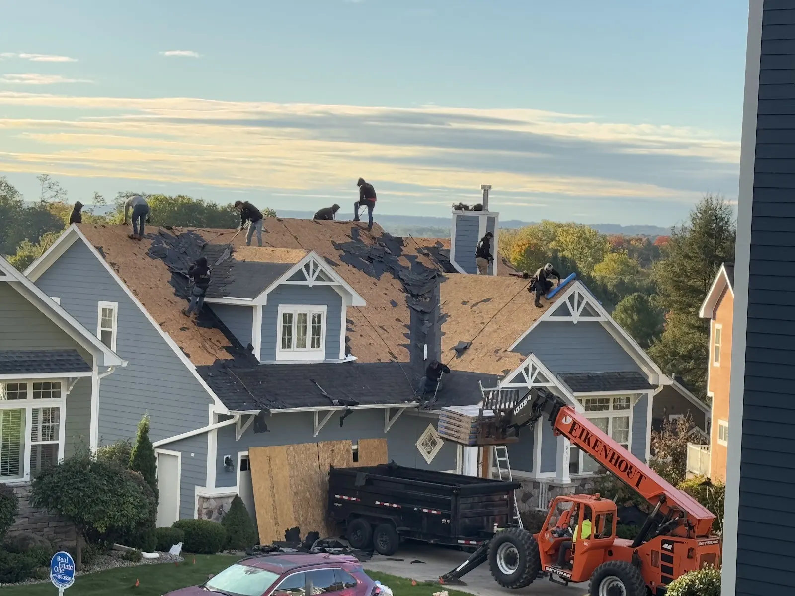 A roof tear-off underway with a dump truck and forklift on site in Northern Michigan.