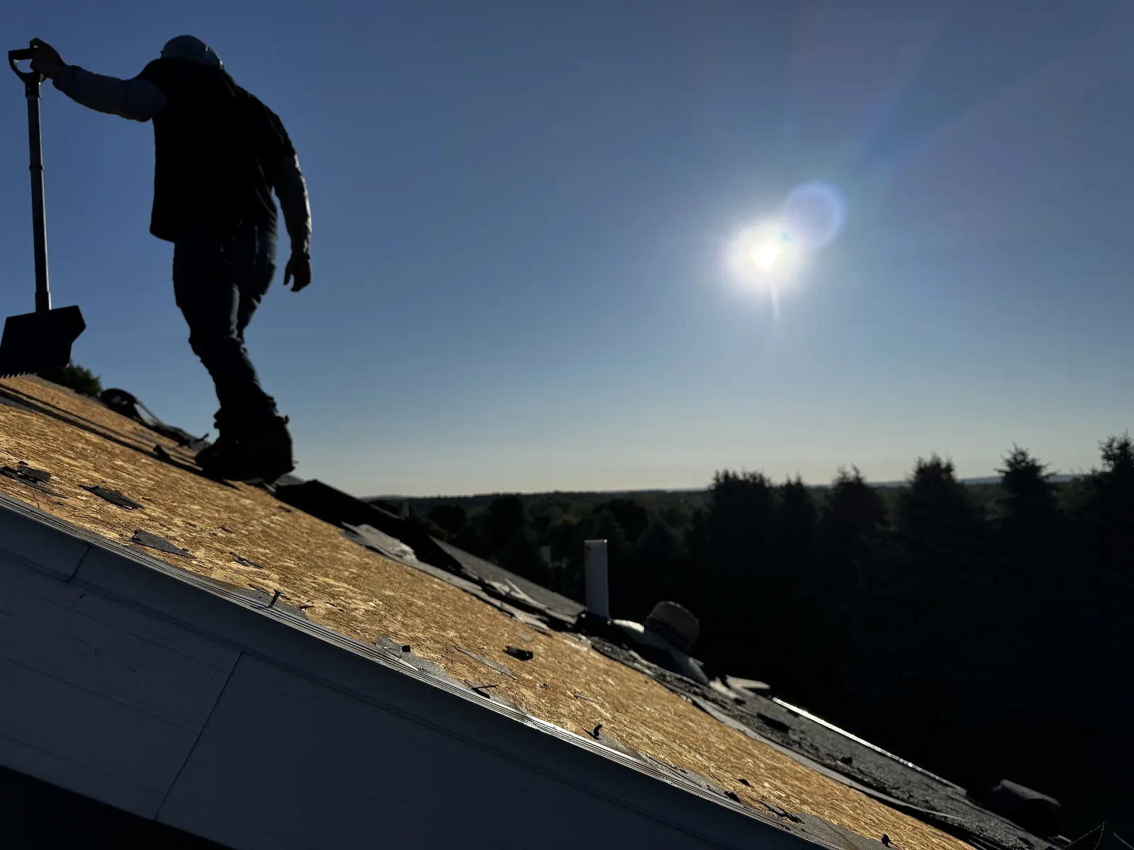 A worker stripping off an old, worn roof, a clear sign it was time for a replacement.